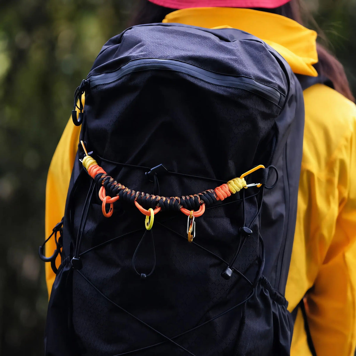 EDCForce paracord backpack strap in black and orange braided across the front of a black hiking backpack