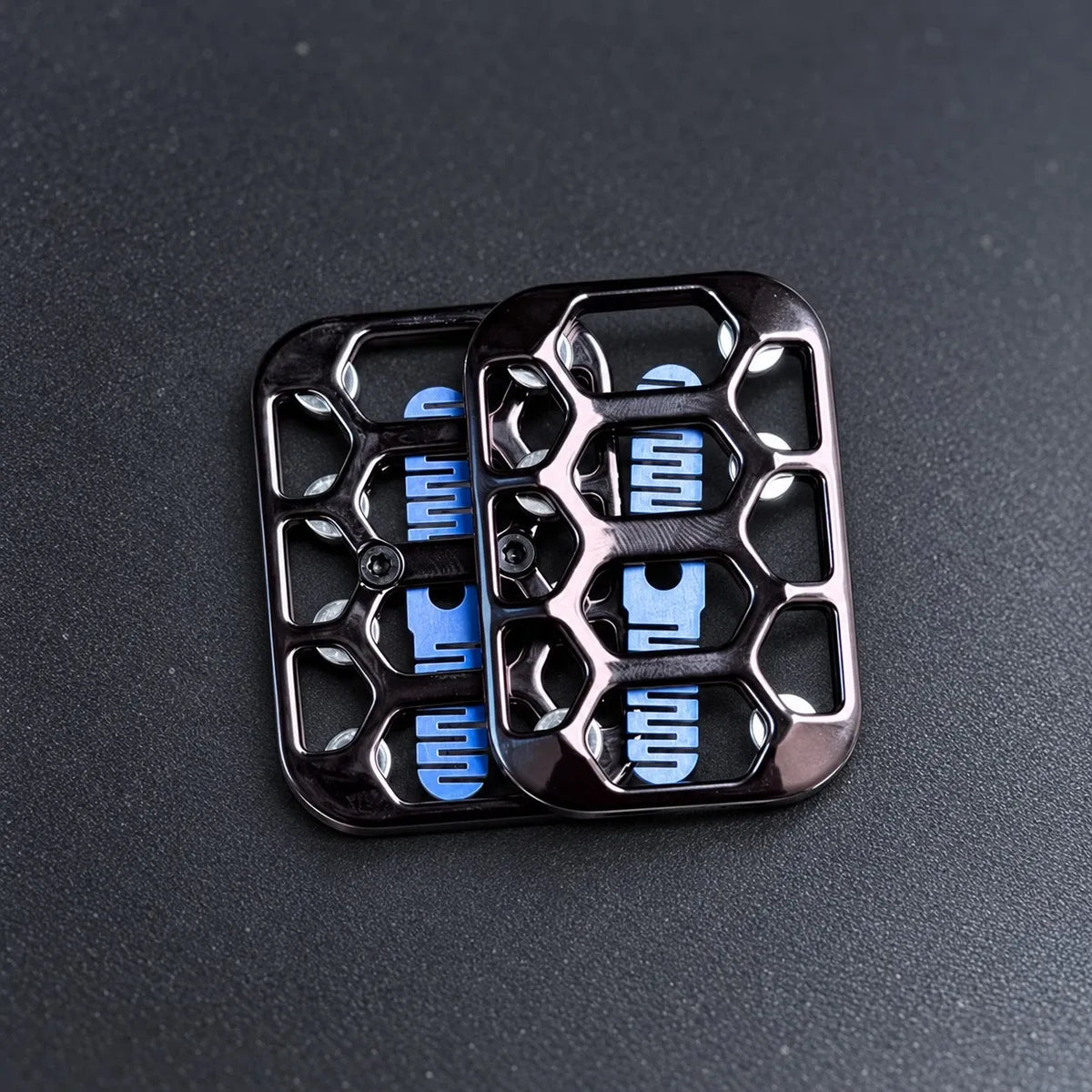 Black and gunmetal magnetic fidget sliders on a bead-blasted steel desk